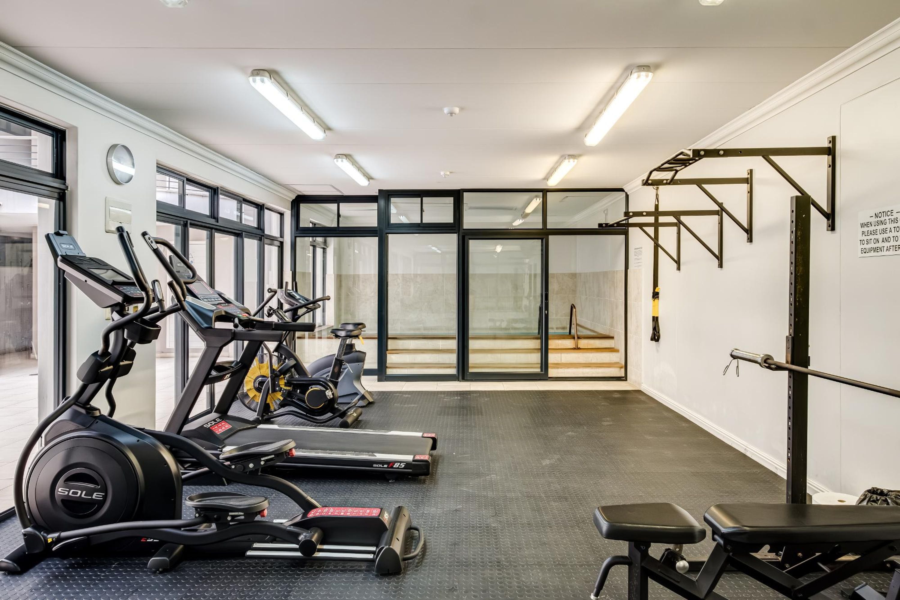 A gym with treadmills, an elliptical, a bench, and a squat rack.