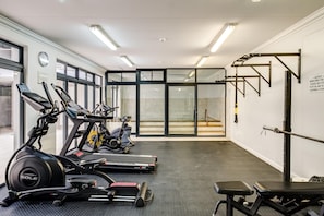 A gym with treadmills, an elliptical, a bench, and a squat rack. - Cape Town Deluxe City Apartment Hafen Views (Cape Town)