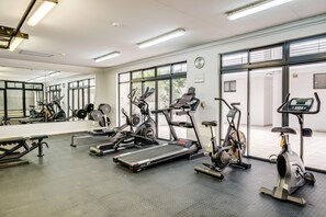 Un gimnasio con cintas de correr, elípticas y máquinas de pesas.