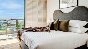 Un dormitorio con una cama grande, vistas de la ciudad y un balcón con una silla.
