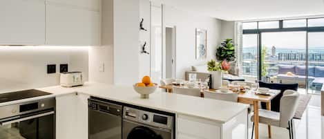 A modern kitchen with built-in appliances, a dining area with a view, and a large window.
