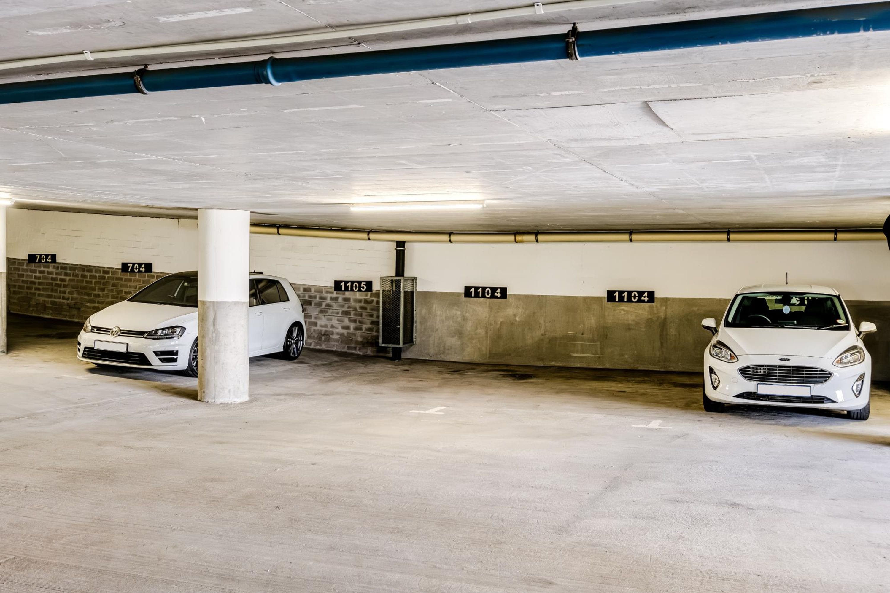 A parking garage with two white cars parked under columns, each marked with a number.