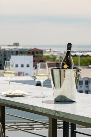 A table with two glasses of white wine, a bottle of wine in a metal bucket, and a plate with a fork and knife. - Cape Town Deluxe City Apartment Hafen Views (Cape Town)