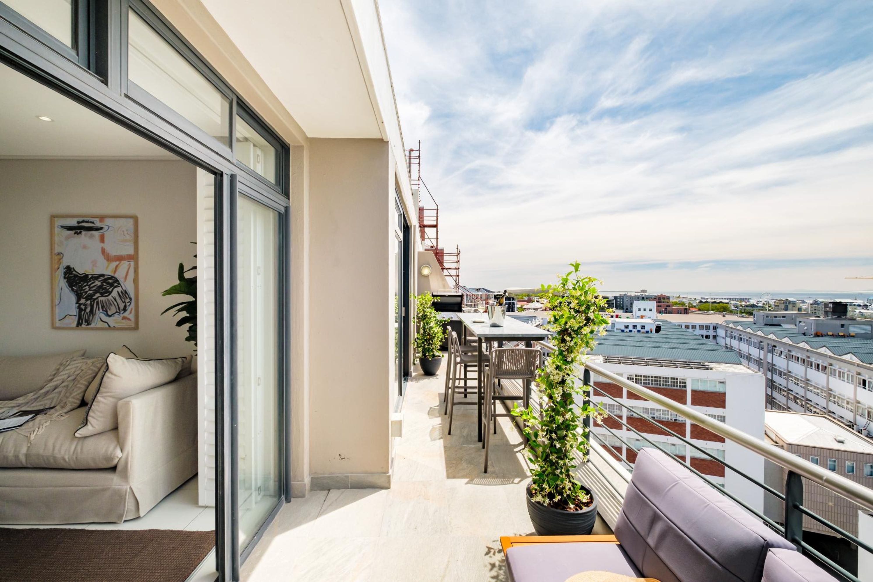 A balcony with a sofa, a dining table, and potted plants.