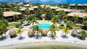 Een resort met een centraal gelegen zwembad, palmbomen en strandgebieden.