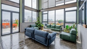 A spacious balcony with large windows, green seating, and potted plants. - w Comfy 1BR w Perfect Balcony in Casco View (Panama City)