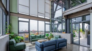 A spacious indoor area with large windows, green seating, and potted plants. - w Comfy 1BR w Perfect Balcony in Casco View (Panama City)