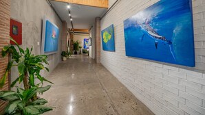 A hallway with white brick walls, large blue paintings, and potted plants. - w Comfy 1BR w Perfect Balcony in Casco View (Panama City)