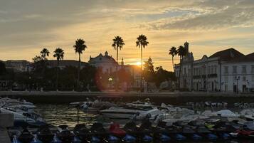 Eine Marina mit vertäuten Booten, ein Sonnenuntergang im Hintergrund und Gebäude entlang des Ufers.