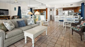 A spacious living area with a sofa, coffee table, and chairs, a kitchen with white appliances, and a dining area with a table and chairs. - Marigot Beach-Beautiful 3 Bedroom Direct Oceanfront Condo! (Ocean City)