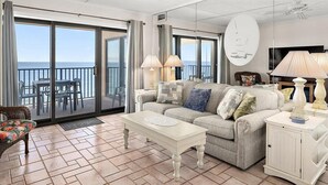A spacious living area with a sofa, coffee table, and a view of the sea through large sliding doors. - Marigot Beach-Beautiful 3 Bedroom Direct Oceanfront Condo! (Ocean City)