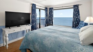 A bedroom with a bed, a TV, a nightstand, and a view of the sea. - Marigot Beach-Beautiful 3 Bedroom Direct Oceanfront Condo! (Ocean City)