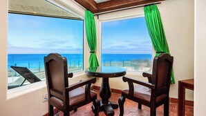 A room with a round table and two chairs, a window with a view of the ocean, and green curtains. - Villa del Pacifico - Luxury Oceanfront Solana Beach Vacation Rental (Solana Beach)