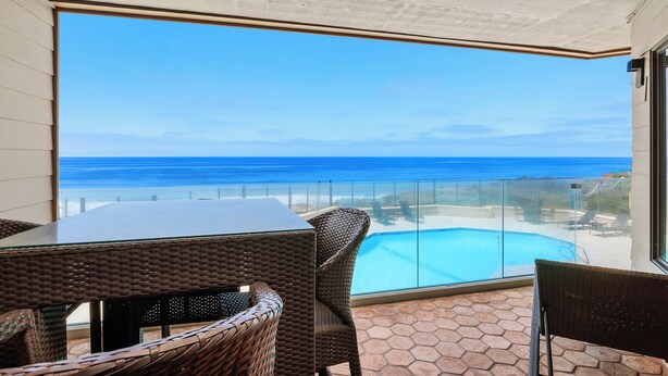 A balcony with wicker furniture overlooking a swimming pool and the ocean. - Villa del Pacifico - Luxury Oceanfront Solana Beach Vacation Rental (Solana Beach)