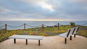 A bench and a table on a sandy area with a view of the ocean and a cloudy sky. - Villa del Pacifico - Luxury Oceanfront Solana Beach Vacation Rental (Solana Beach)