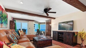 A spacious living room with a leather sofa, a wooden coffee table, and a television on a cabinet. - Villa del Pacifico - Luxury Oceanfront Solana Beach Vacation Rental (Solana Beach)