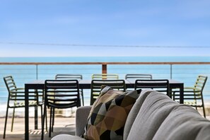 A beachside seating area with a table and chairs, overlooking the sea.