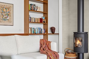 A living room with a sofa, a bookshelf, a fireplace, and a woven basket.