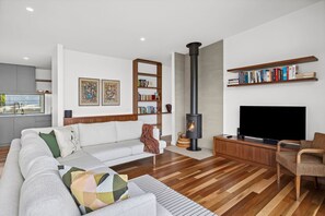 A modern living room with a sofa, a television, a bookshelf, and a fireplace.