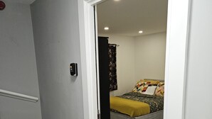 Un dormitorio con cama, mesita de noche y teléfono en la pared.