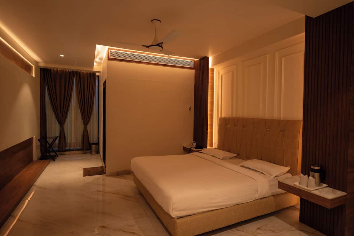 A modern hotel room with a large bed, a ceiling fan, and a TV mounted on the wall.