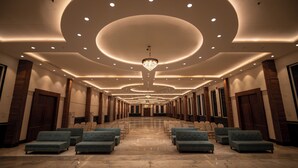 A spacious hotel lobby with a long row of seating, a large chandelier, and a polished marble floor. - Hotel J.K. Celebration (Jabalpur)