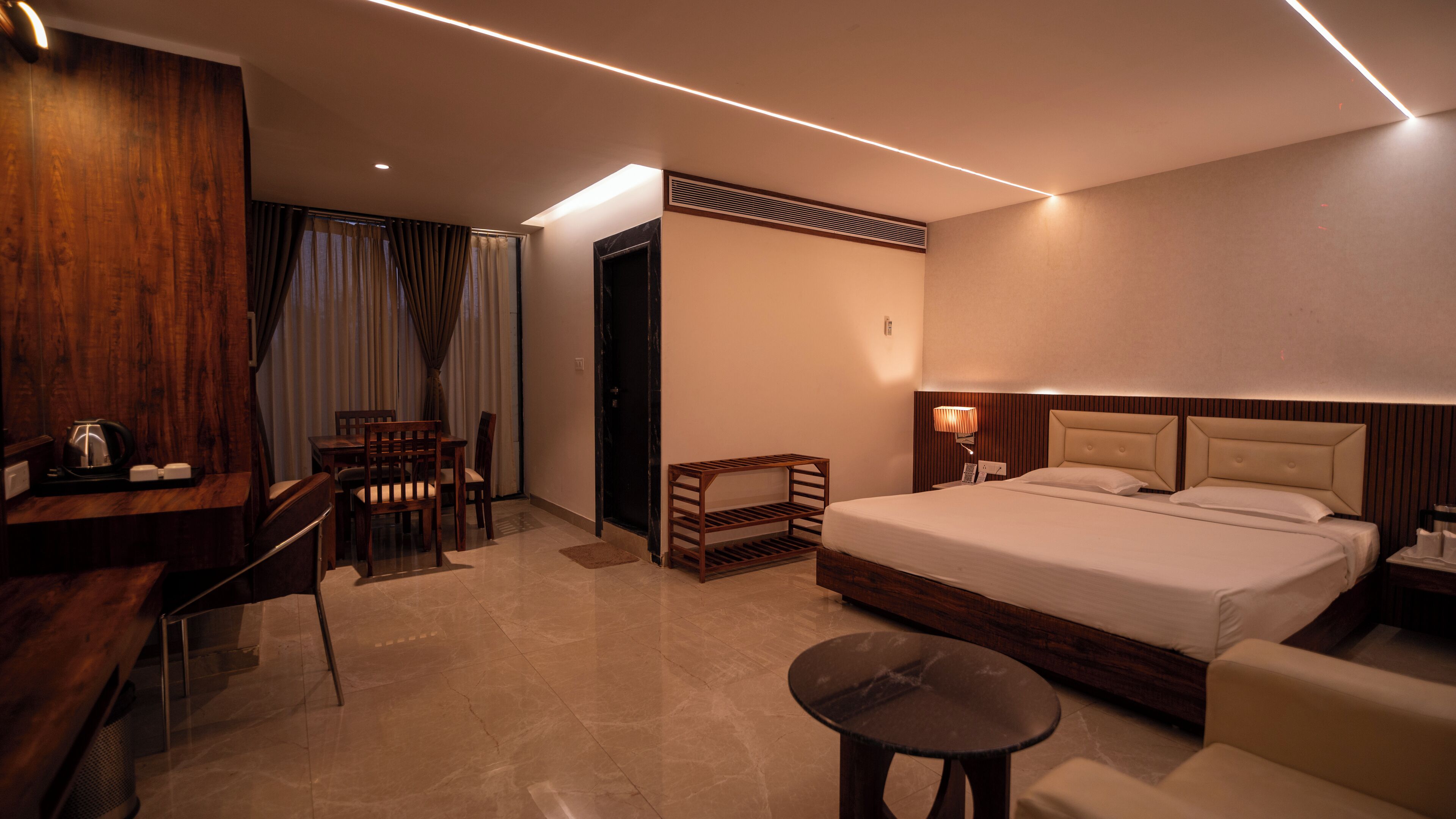 Une chambre d’hôtel moderne dotée d’un grand lit, d’un bureau avec une chaise, d’une petite table et d’un coin salon avec un canapé.