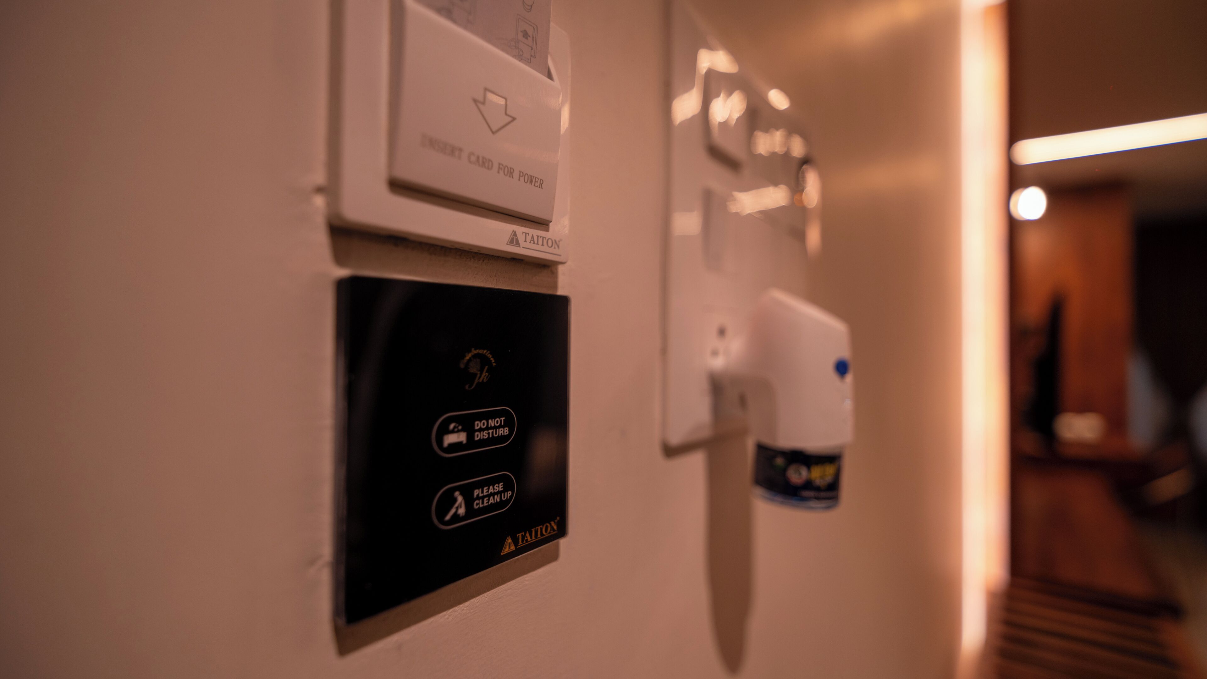 A wall with a power card reader, a sign instructing to not disturb, and a cleaning request sign.