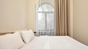 A hotel room with a large bed, white bedding, and sheer curtains. - Apartment on Khanjyan street (Yerevan)
