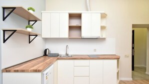 A compact kitchen with white cabinetry, a wooden countertop, and a built-in dishwasher. - Apartment on Khanjyan street (Yerevan)
