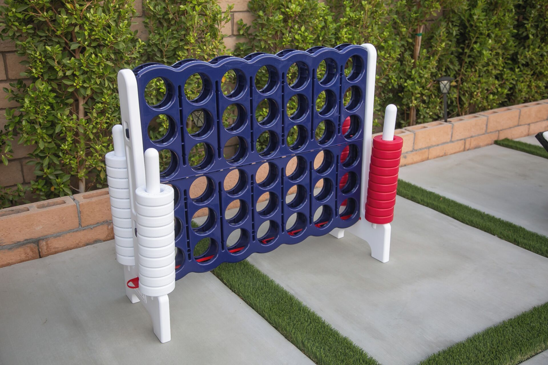 Un tablero azul y blanco con agujeros, sobre una superficie de concreto con césped artificial verde.