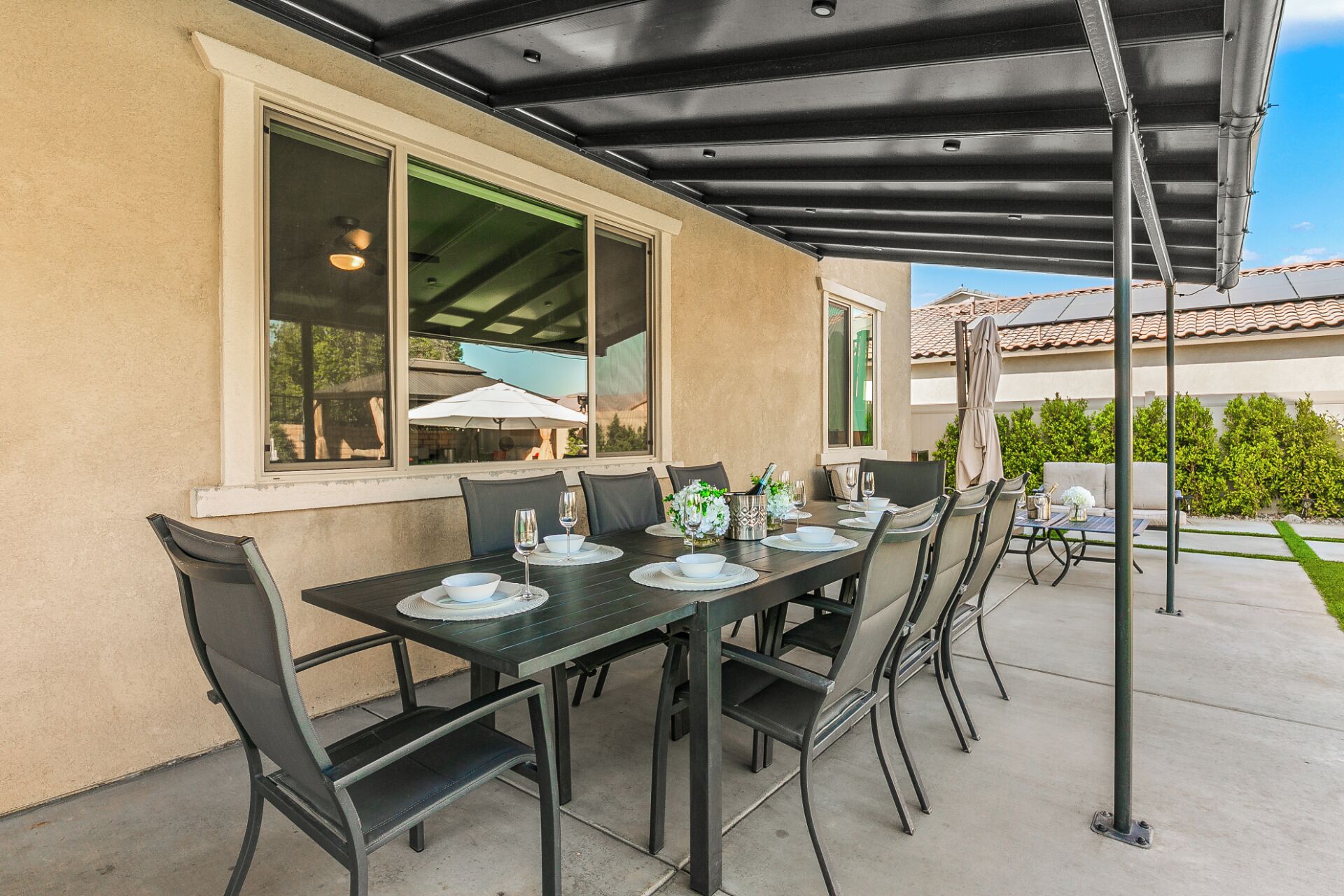 Eine Außenpatio mit überdachtem Essbereich, darunter ein Tisch für vier Personen, Stühle und eine Pergola.