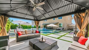 A covered outdoor area with a pool, seating, and a ceiling fan.