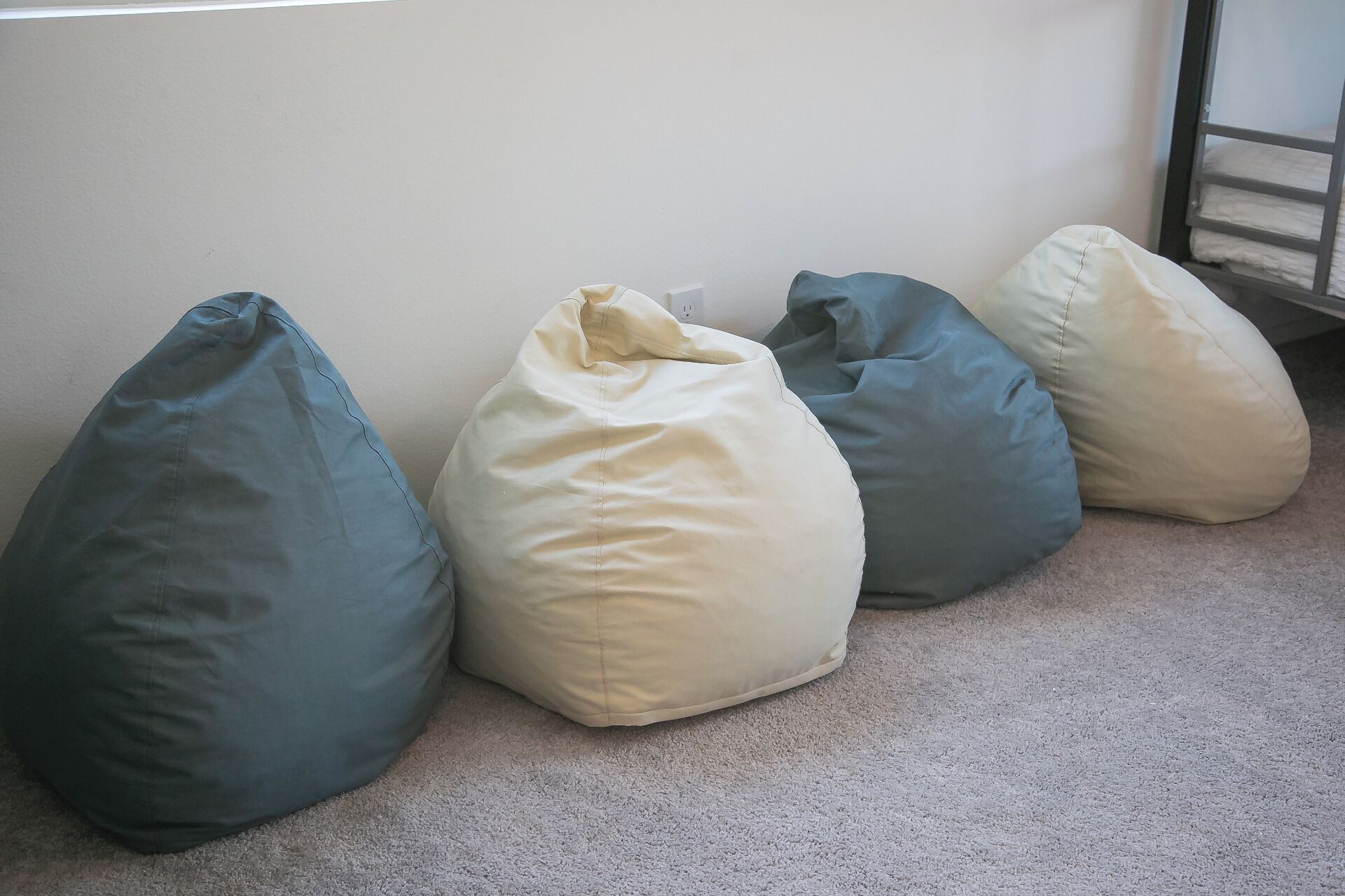 Four bean bags in different colors arranged against a wall.