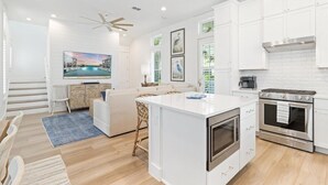 A modern kitchen with white cabinetry, a central island, a built-in oven, and a ceiling fan.