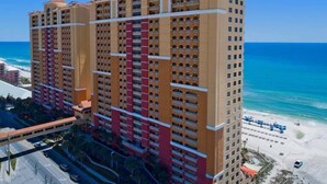 Un hotel moderno de altura con varios balcones, vista al mar y zona de estacionamiento.