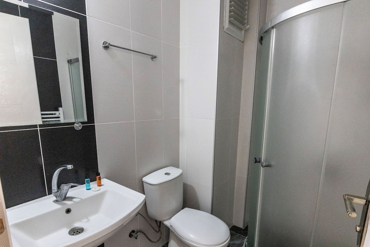 A bathroom with a white sink, toilet, and a shower enclosure.