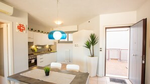 A modern kitchen with white cabinets, a dining table with chairs, a potted plant, and a view of a balcony. - Casa Adelaide, near the sea and the historic center with a panoramic terrace (Senigallia)