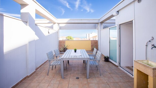 An outdoor patio with a table and chairs, a sliding door, and a view of buildings in the background. - Casa Adelaide, near the sea and the historic center with a panoramic terrace (Senigallia)
