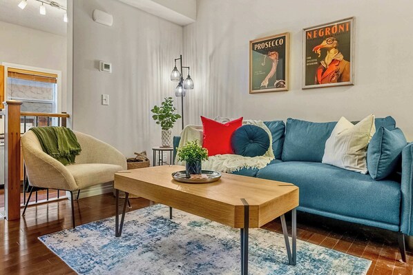 Relax in this stylish living room with a sofa, coffee table, and armchair, offering a view of the outside through the large window.