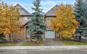 Stunning residential building with a central entrance and two garages, surrounded by mature trees.