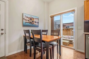 Enjoy meals in this cozy dining area with a table for four, a painting of a European town, and a sliding door to an outdoor deck.