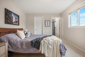 Enjoy a restful stay in this stylish room featuring a large bed, cityscape painting, and walk-in closet with a mirror and window.