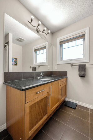 Bathroom features a granite countertop, stainless steel sink, and a wall-mounted mirror with a light fixture.