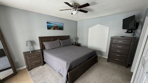 A bedroom with a bed, nightstands, a dresser, a ceiling fan, a TV, and a window with shutters. - Villa Crayson 3 Bedroom Home (Kissimmee)