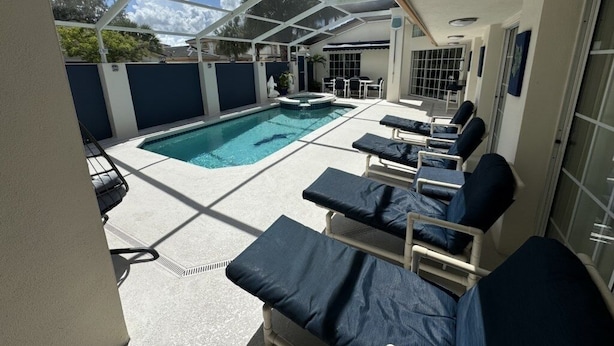 A covered outdoor swimming pool area with lounge chairs and a hot tub. - Villa Crayson 3 Bedroom Home (Kissimmee)