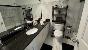 A modern bathroom with a black countertop sink, white toilet, and a mirrored wall. - Villa Crayson 3 Bedroom Home (Kissimmee)