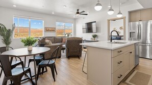 Une cuisine moderne dotée d’un grand îlot central, d’appareils électroménagers en acier inoxydable et d’un coin repas avec une table et des chaises.