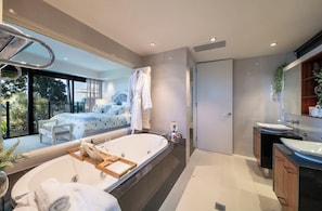 A modern bathroom with a large bathtub, two sinks, and a large mirror.
