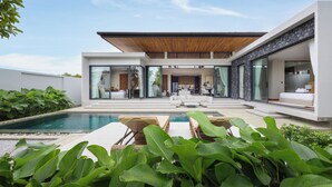 Ein modernes Haus mit Pool, Sitzgelegenheit im Freien und einer überdachten Terrasse.